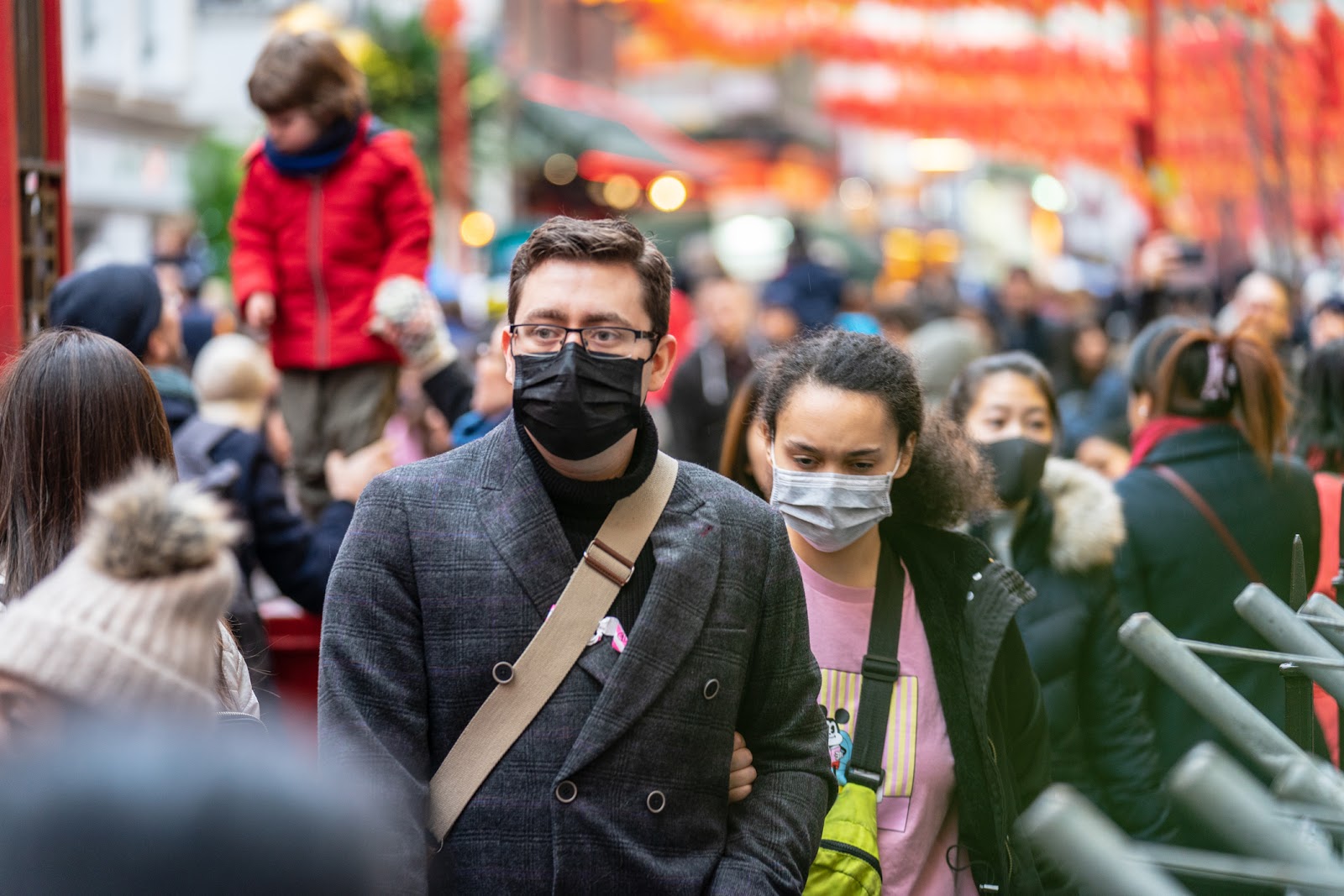 Crowd of people walking down the street with masks on